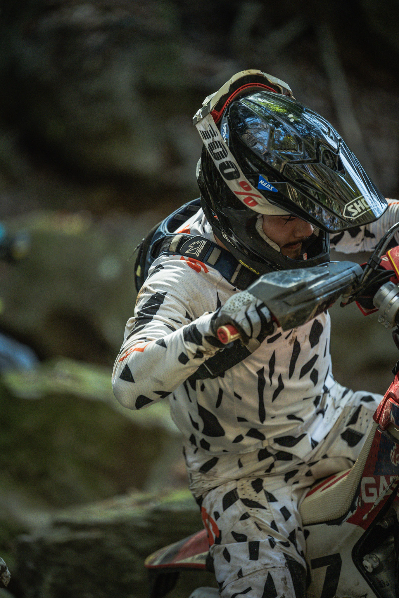 Rider's hands on grips, mud splattered